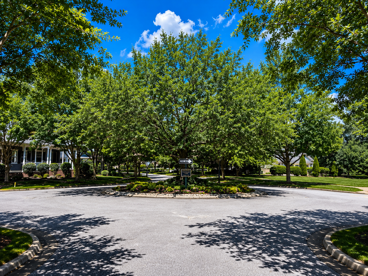 A shaded landscaped roundabout in Oak Park ringed by mature trees and a front-porch home
